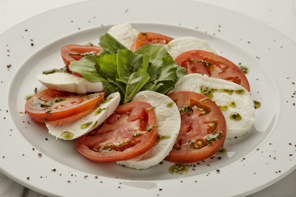 Caprese salad with sliced tomatoes, mozzarella and basil on a white plate